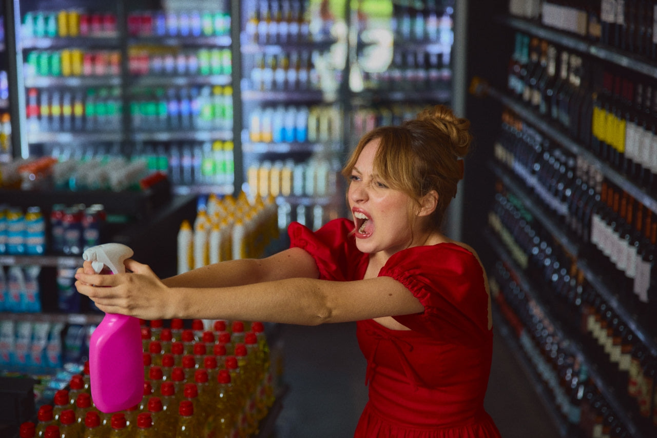 Frustrated shopper holds chemical spray bottle in cleaning aisle, highlighting concerns about toxins in household products