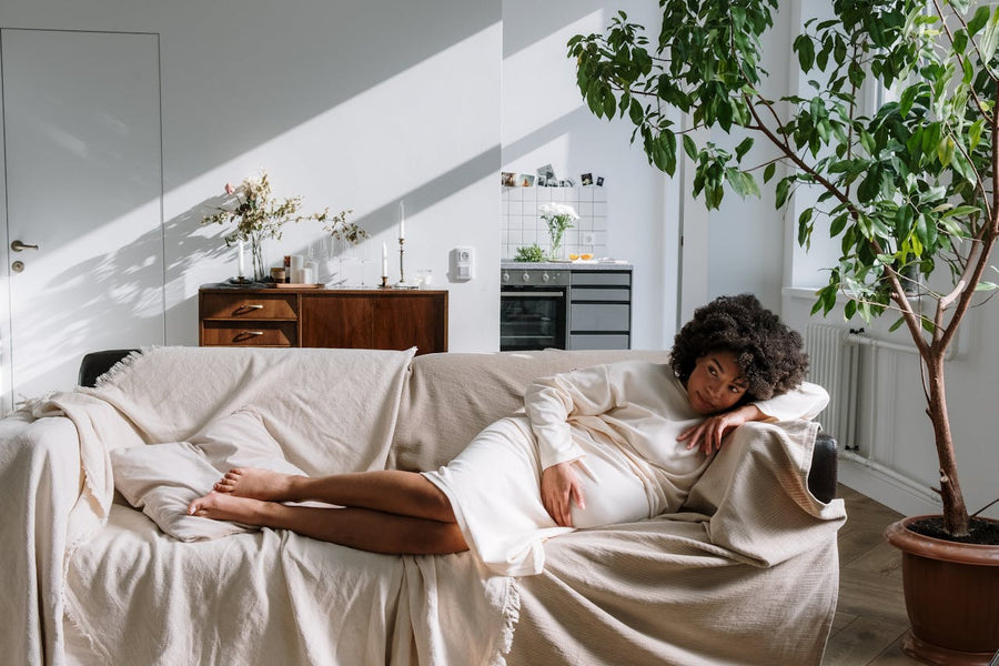 Pregnant woman resting on a sofa in a bright living room highlighting the need for safe, non-toxic cleaning products at home.